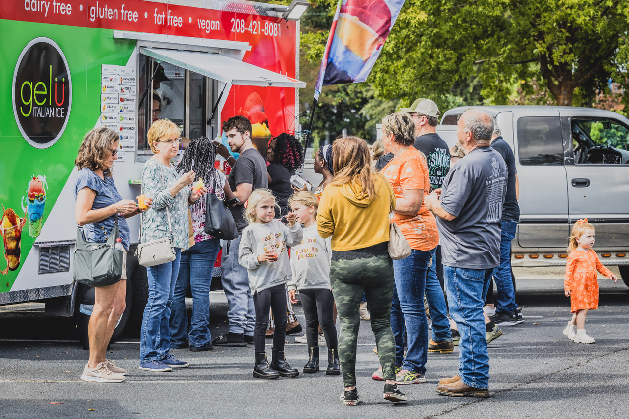 Attendees will enjoy various food trucks and vendors at Spring Fest. A group of festival attendees stand around a shed ice truck enjoying a tasty treat.