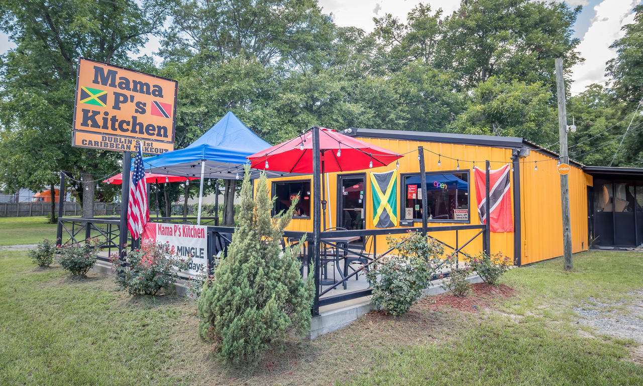 Exterior view of Mama P's Kitchen showing off the patio seating and Jamaican and American flags.