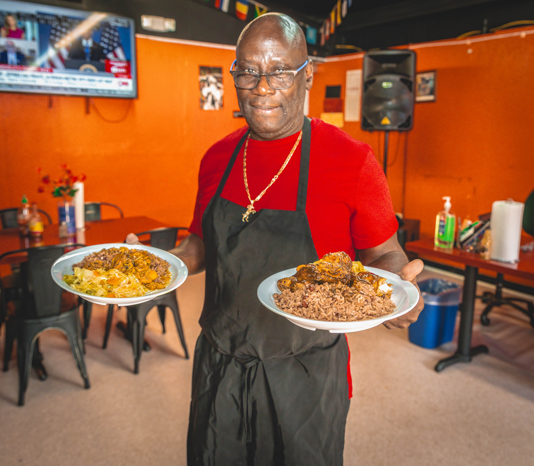 Mr. Chris serving two heaping plates of food at Mama P's Kitchen.