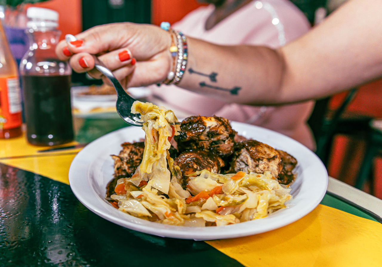 A woman scooping up a forkful of cabbage at mama P's Kitchen.