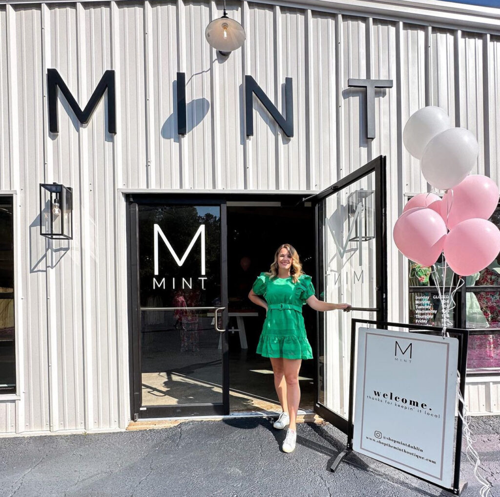 exterior of Mint Boutique with owner Kelly Hightower wearing green dress