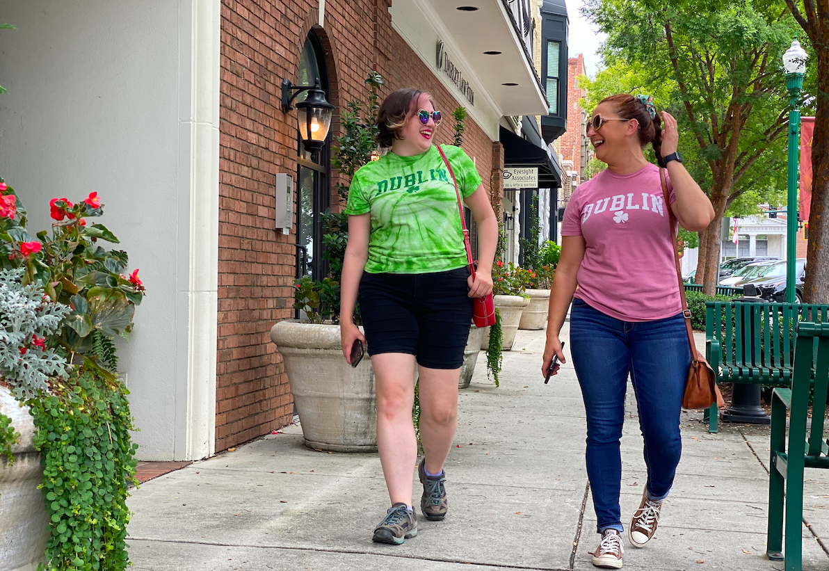 Two women walking on the sidewalk and laughing in downtown Dublin GA.