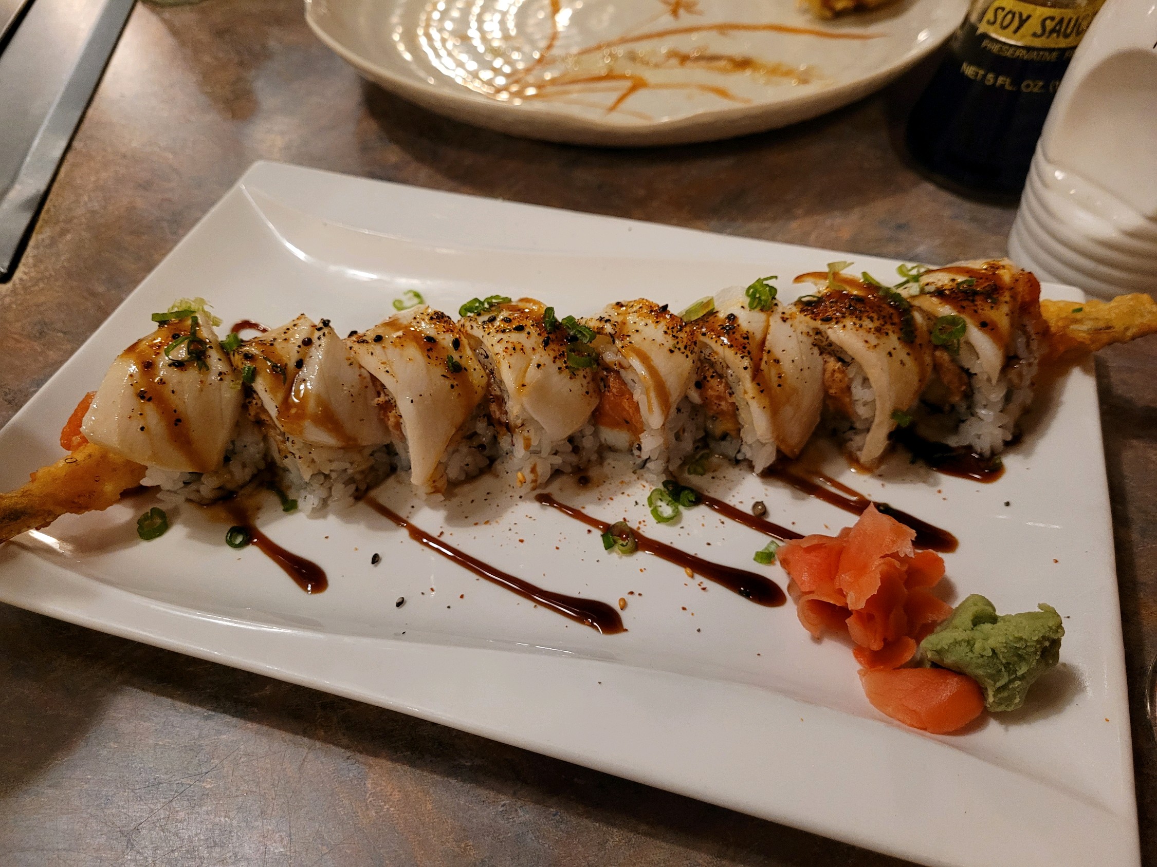Beautiful sushi roll lays across rectangular plate with ginger and wasabi Family Fest