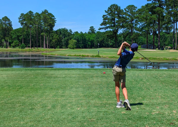 Man launches a golf ball during a green acres tournament