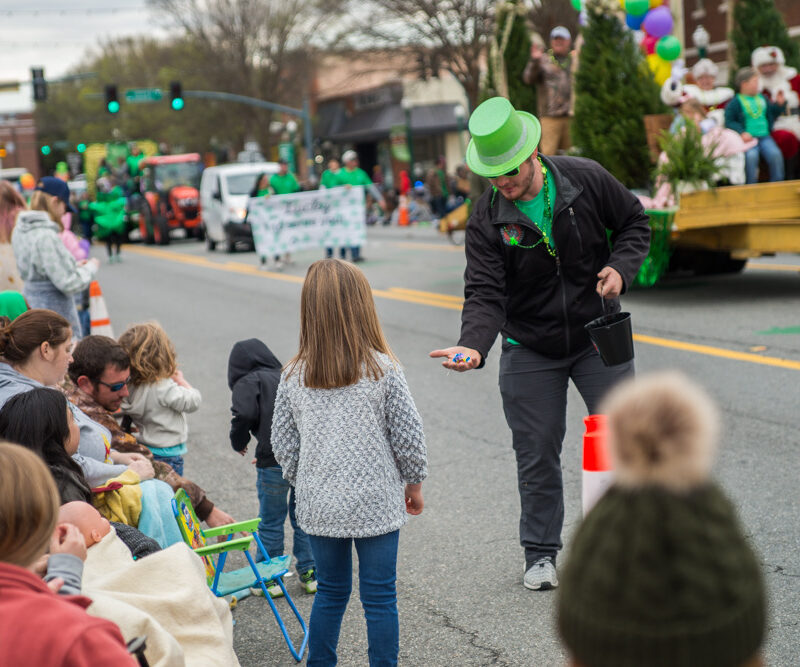 man handing children candy at St. Patrick's parade