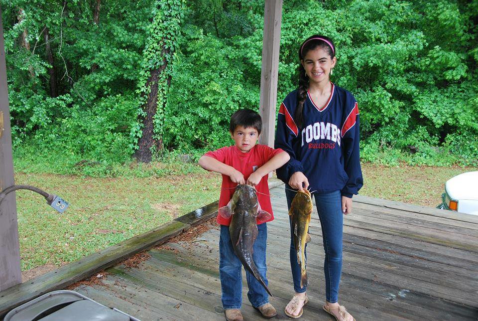 Two kids with a catfish for Hunting for the Cure on a dock