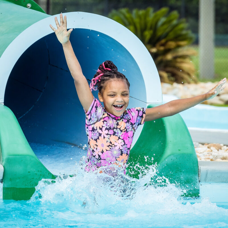 Excited little girl slides down the covered slide at Southern Pines Water Park- Slide into September