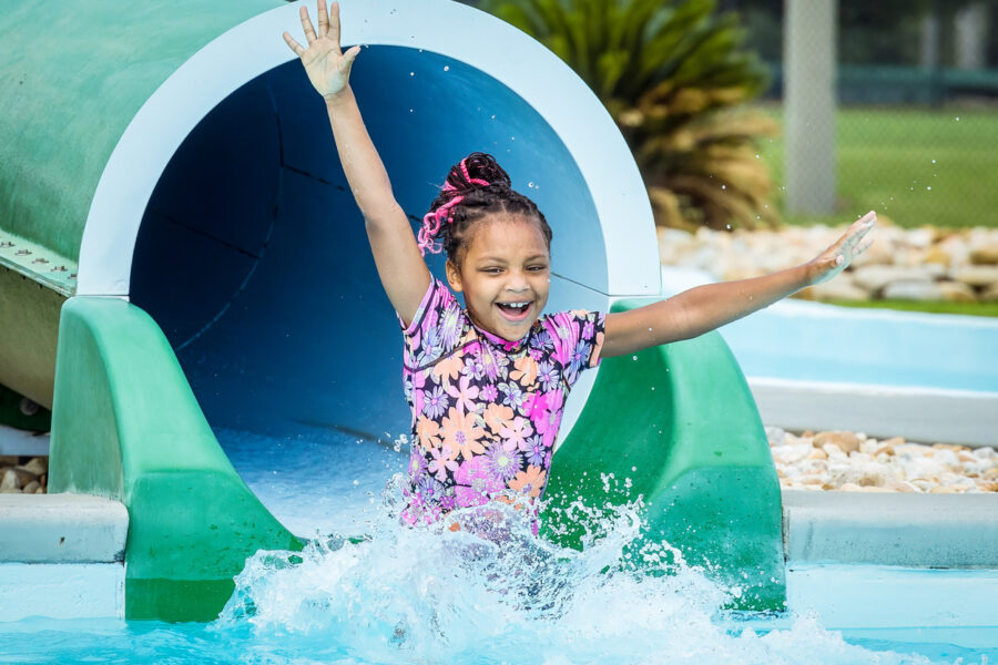 Excited little girl slides down the covered slide at Southern Pines Water Park- Slide into September