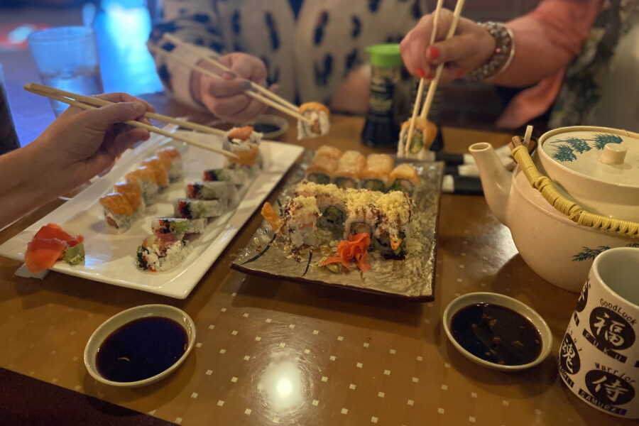 Assorted plates of sushi and pot of green tea being shared at Little Tokyo.