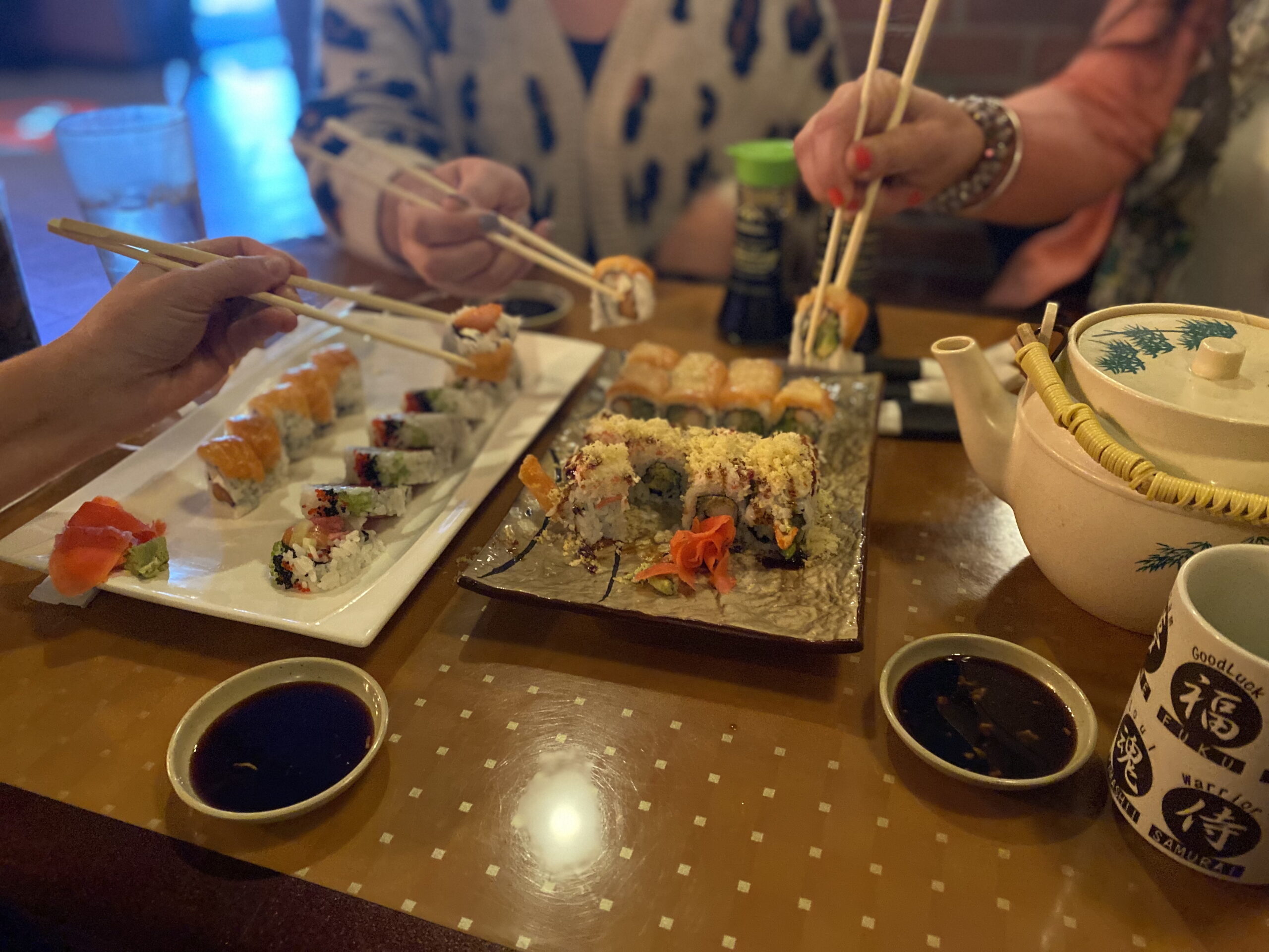 Assorted plates of sushi and pot of green tea being shared at Little Tokyo.