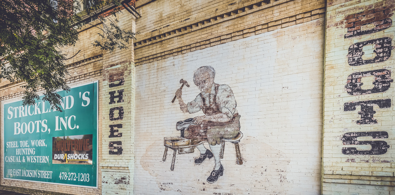 mural of a shoe cobbler on the exterior wall of Strickland's Boots.