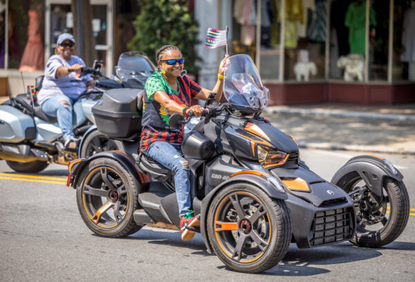 Woman on large motorcycle waves Juneteenth Flag during Taste of Juneteenth Parade