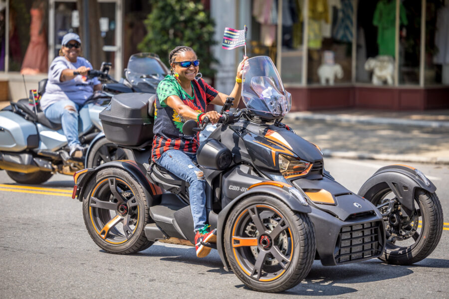 Woman on large motorcycle waves Juneteenth Flag during Taste of Juneteenth Parade