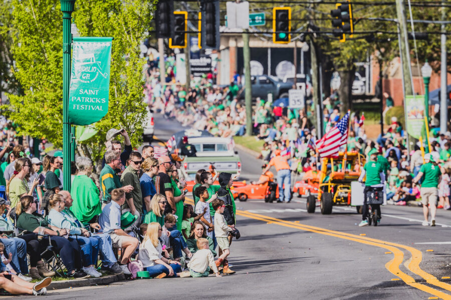 A crowd of people lining the streets watch as parade marchers pass St. Patrick's Parade
