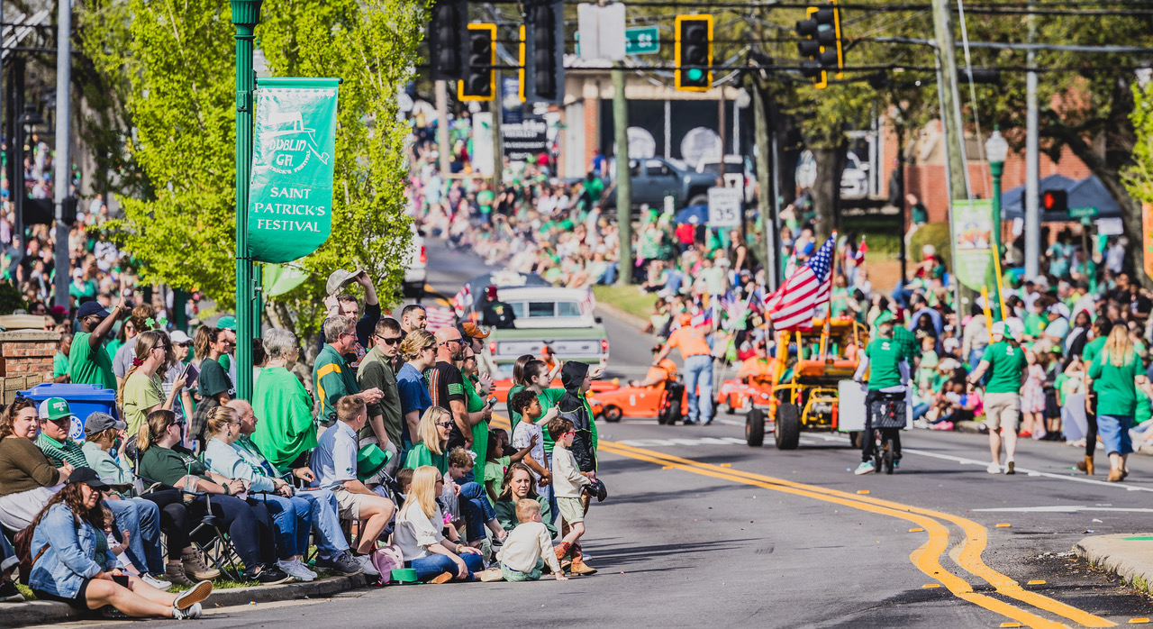 A crowd of people lining the streets watch as parade marchers pass St. Patrick's Parade