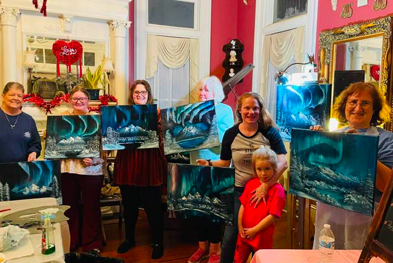 A group of aspiring artists show off their works made during the Paint & Sip at the Page House