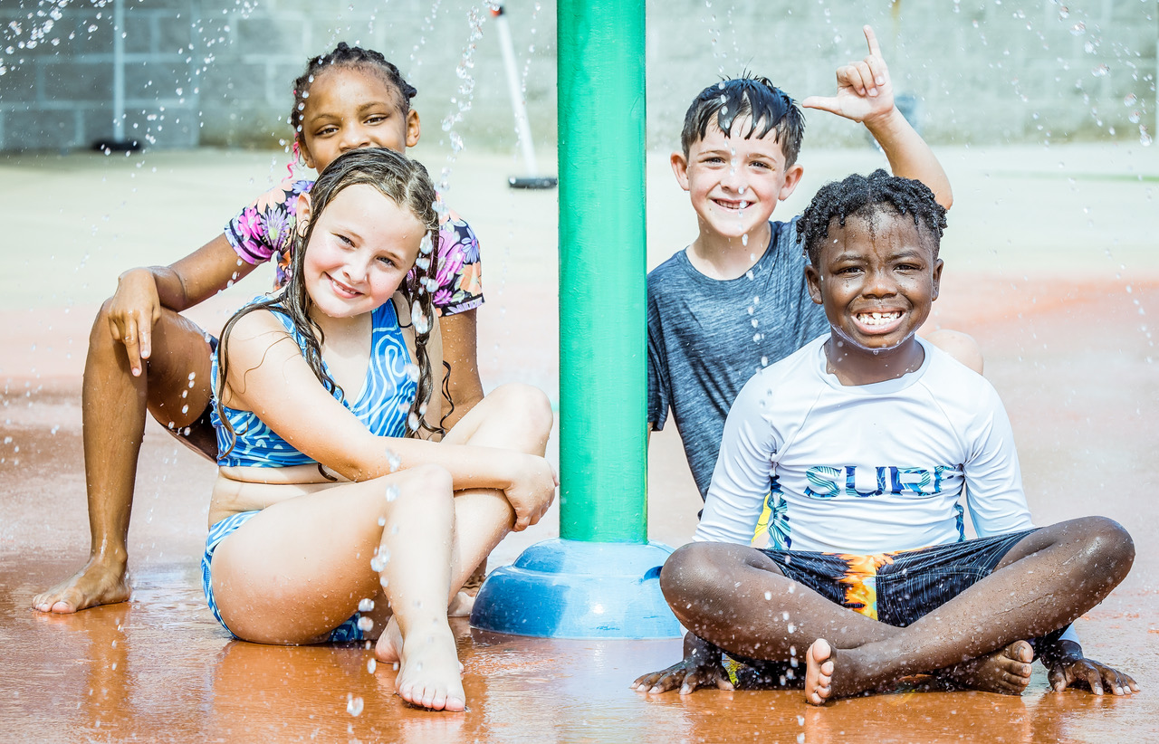 Children under a water nozzle enjoying a sprinkle at Southern Pines Water Park.
