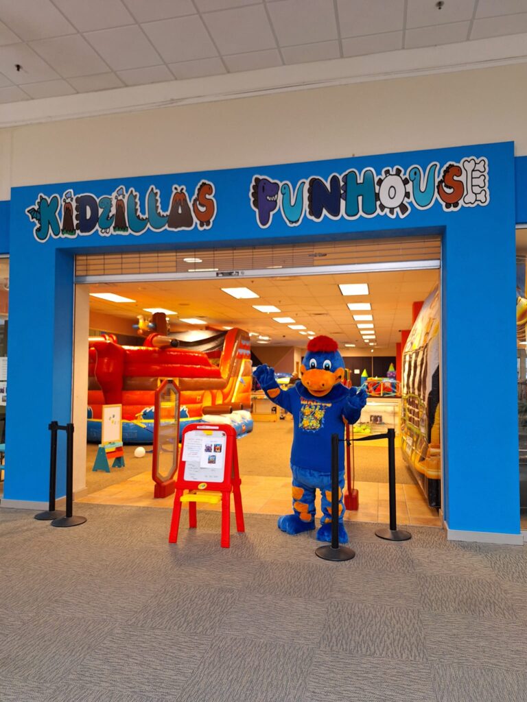 The Kidzilla Funhouse mascot standing in the doorway of the location.