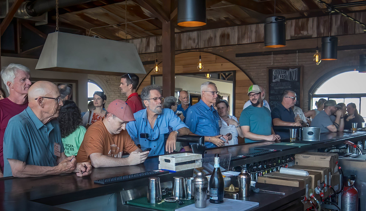 Patrons waiting for beverages at the hewn wood bar of Crooked Finger Brewing.