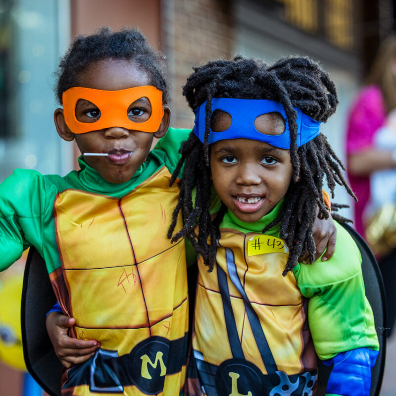 Brothers dressed as Leonardo and Michaelangelo from Teenage Mutant Ninja Turtles search for sweets during Spooky Treats in the Streets