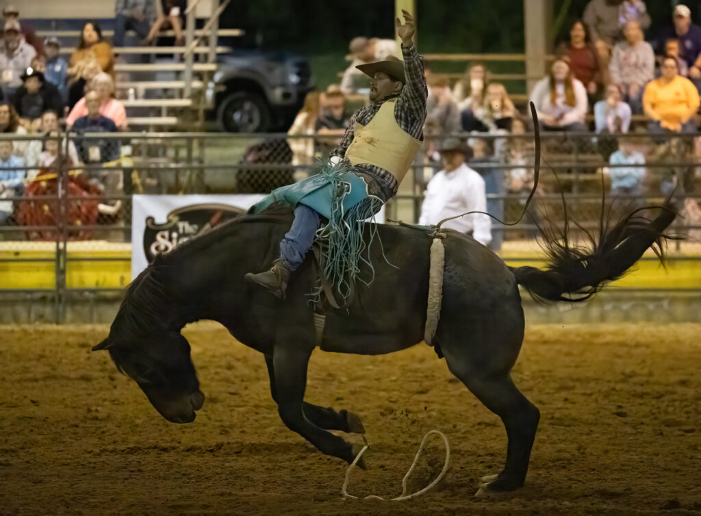 Man rides on bucking bronco during Easterseals Pro Rodeo