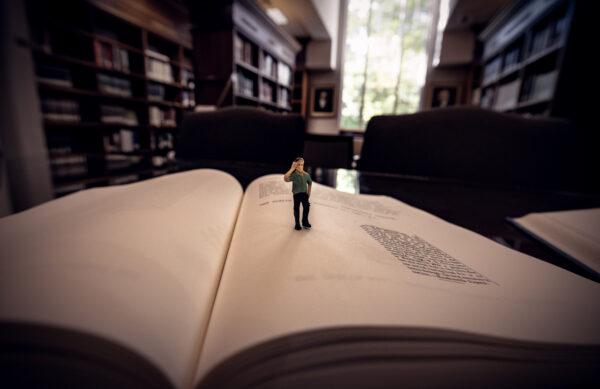 Tiny miniature caricature standing on the open pages of a book at the Laurens County Library. The photo was captured during a Fall Used book Sale.