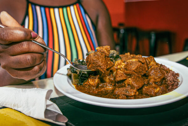 Woman wearing colorful striped shirt digging into a plate of soul food.