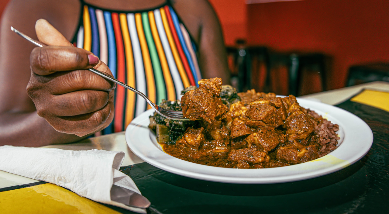 Woman wearing colorful striped shirt digging into a plate of soul food.