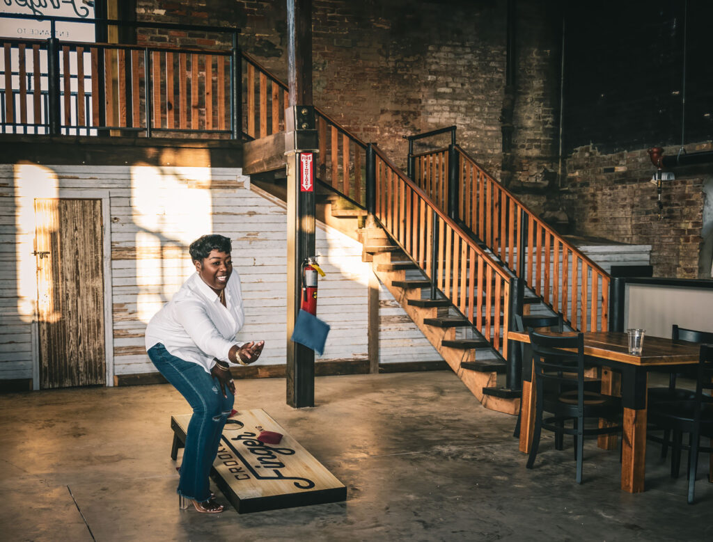 Woman plays cornhole at Crooked Finger Brewing to have more fun for her 2025 Resolution