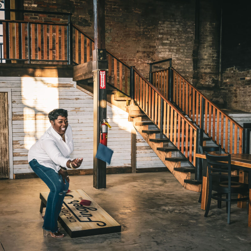 Woman plays cornhole at Crooked Finger Brewing to have more fun for her 2025 Resolution