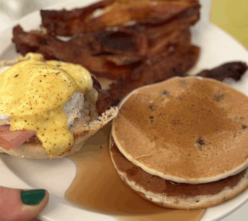 Enjoying Super Sunday Brunch with a plate of bacon, pancakes, and eggs Benedict