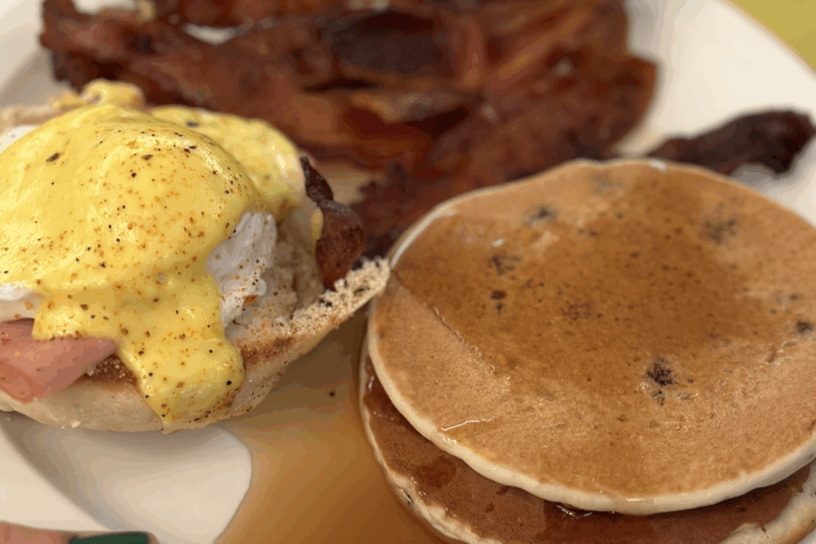 Enjoying Super Sunday Brunch with a plate of bacon, pancakes, and eggs Benedict