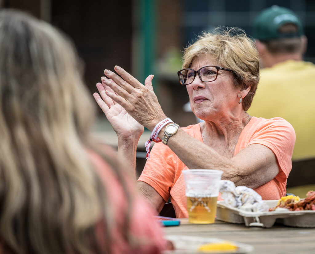 Lady attending a festival clapping along to music. Festivals like this contribute to the tourism economic impact in Dublin and Laurens County.