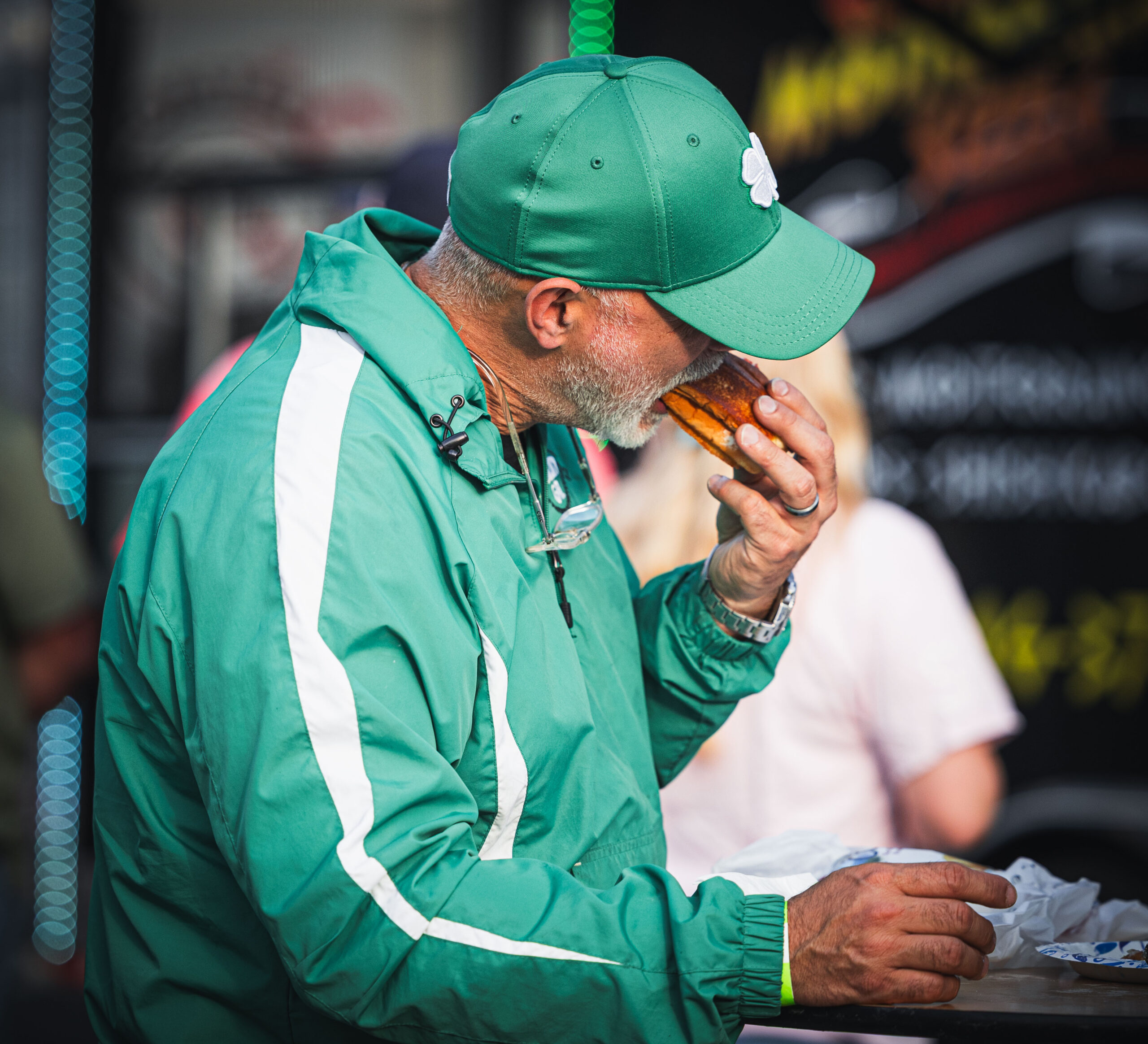 Man dressed in green enjoying a hot dog from a vendor at Dublin St. Patrick's Music & Munchies.