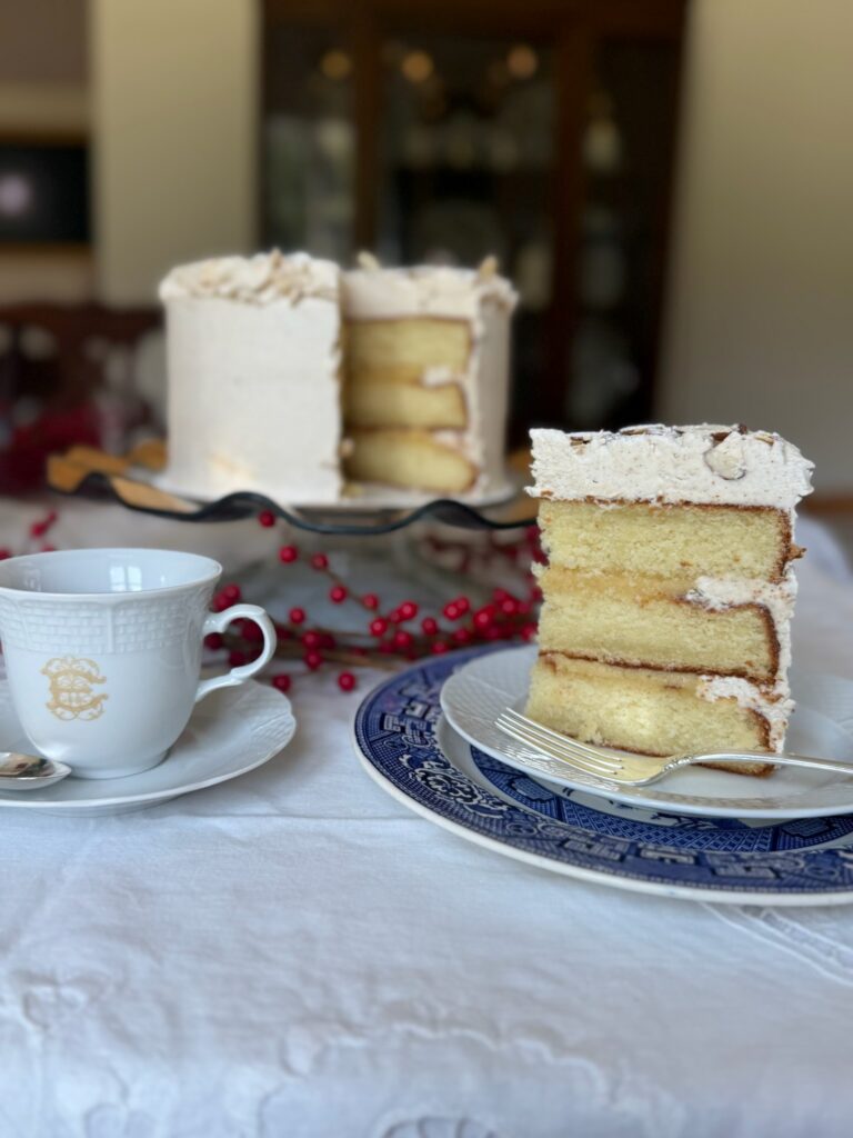A slice of cake next to a coffee mug with the rest of the cake in the background as a teaser for the official 2026 Dublin Service League Fair & Marketplace cake