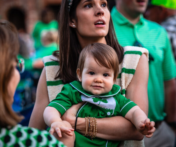 Mom holds onto her baby in a crowd - Littlest Leprechaun Contest