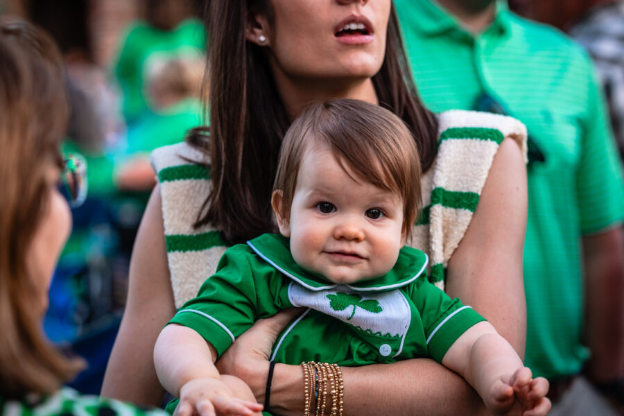 Mom holds onto her baby in a crowd - Littlest Leprechaun Contest