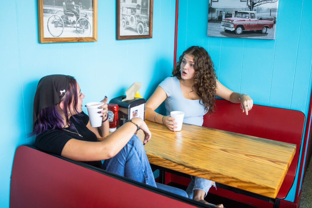 Two women sit at Lou Ann's discussing the 2026 Savor Georgia Culinary Guide