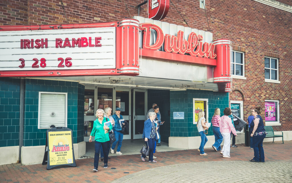 Exterior view of Theater Dublin, where America The Beautiful will take place, with people conversing outside the doors.