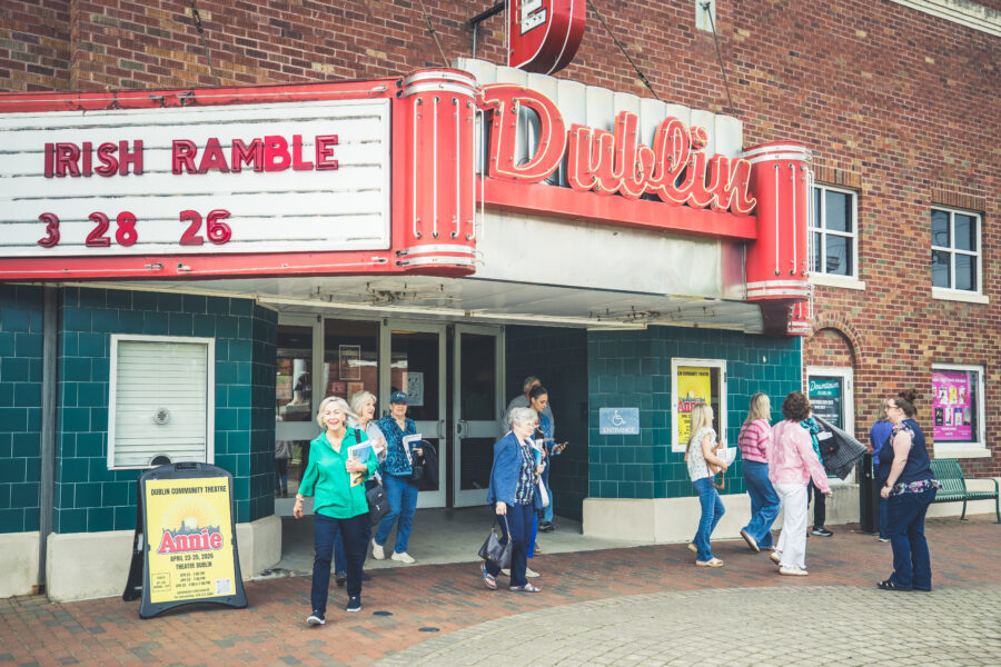 Exterior view of Theater Dublin, where America The Beautiful will take place, with people conversing outside the doors.
