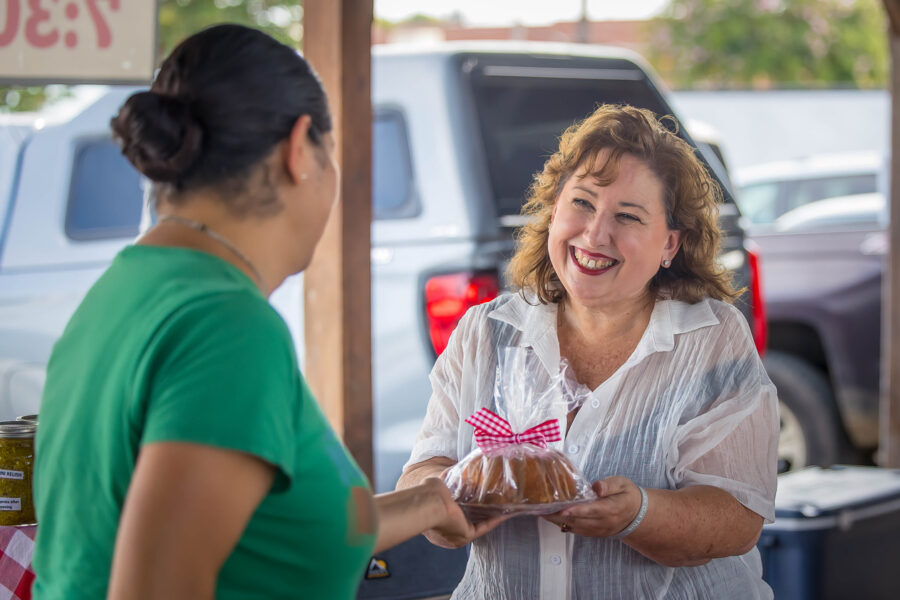 Elaine Avery handing baked good to a patron at the farmers market.