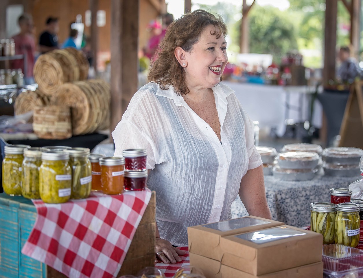 Elaine Avery smiling at passerby's surrounded by canned goods at her table.