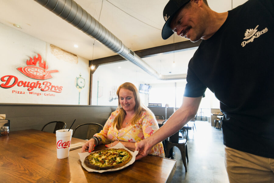 Patron being served a made-to-order pizza but the owner at Dough Bros.