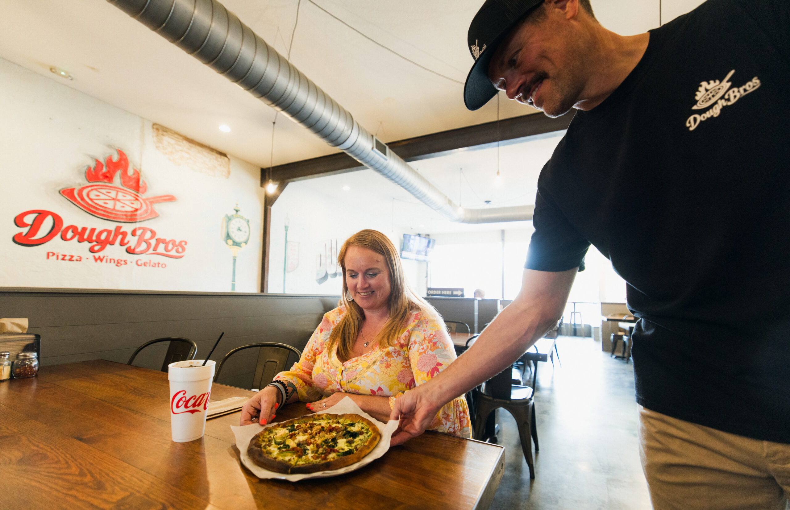 Patron being served a made-to-order pizza but the owner at Dough Bros.