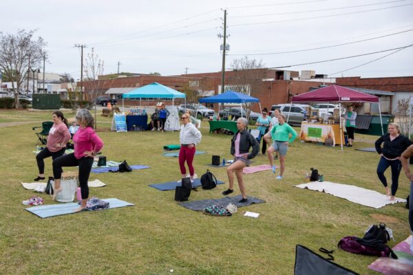 Women do yoga on the Market on Madison lawn during Made to be Well's Women's Well-Being Fest.