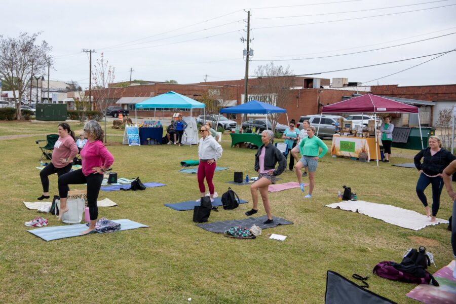 Women do yoga on the Market on Madison lawn during Made to be Well's Women's Well-Being Fest.
