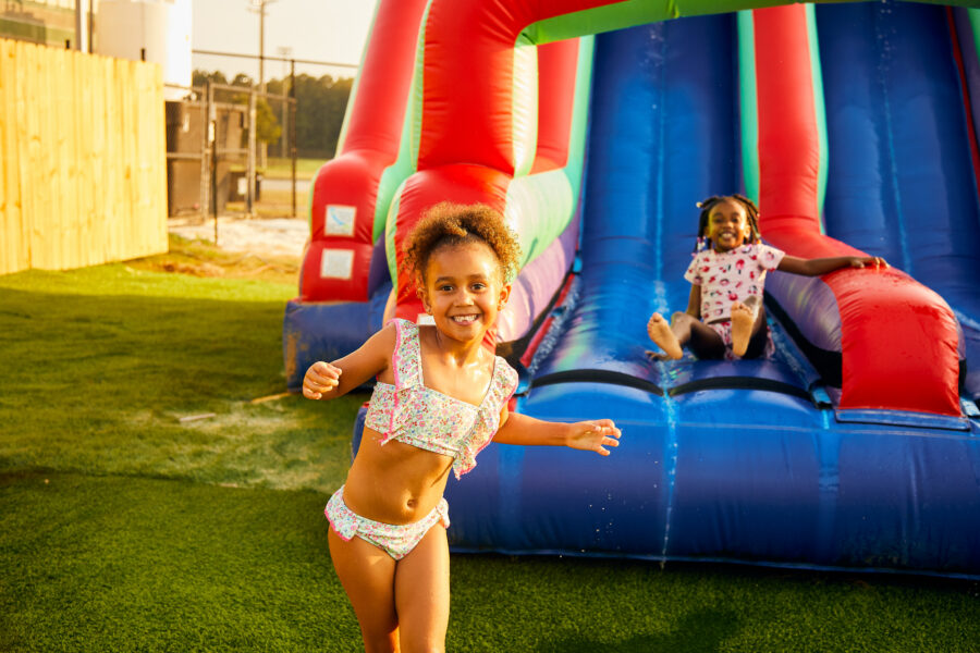 Two young girls playing on a water slide similar to one that will be set up for play at the City Of Dublin water day and movie night.