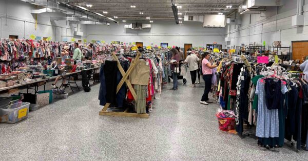 People searching through racks and racks of clothing, used books, shoes, and more at the Emerald City Consignment Sale