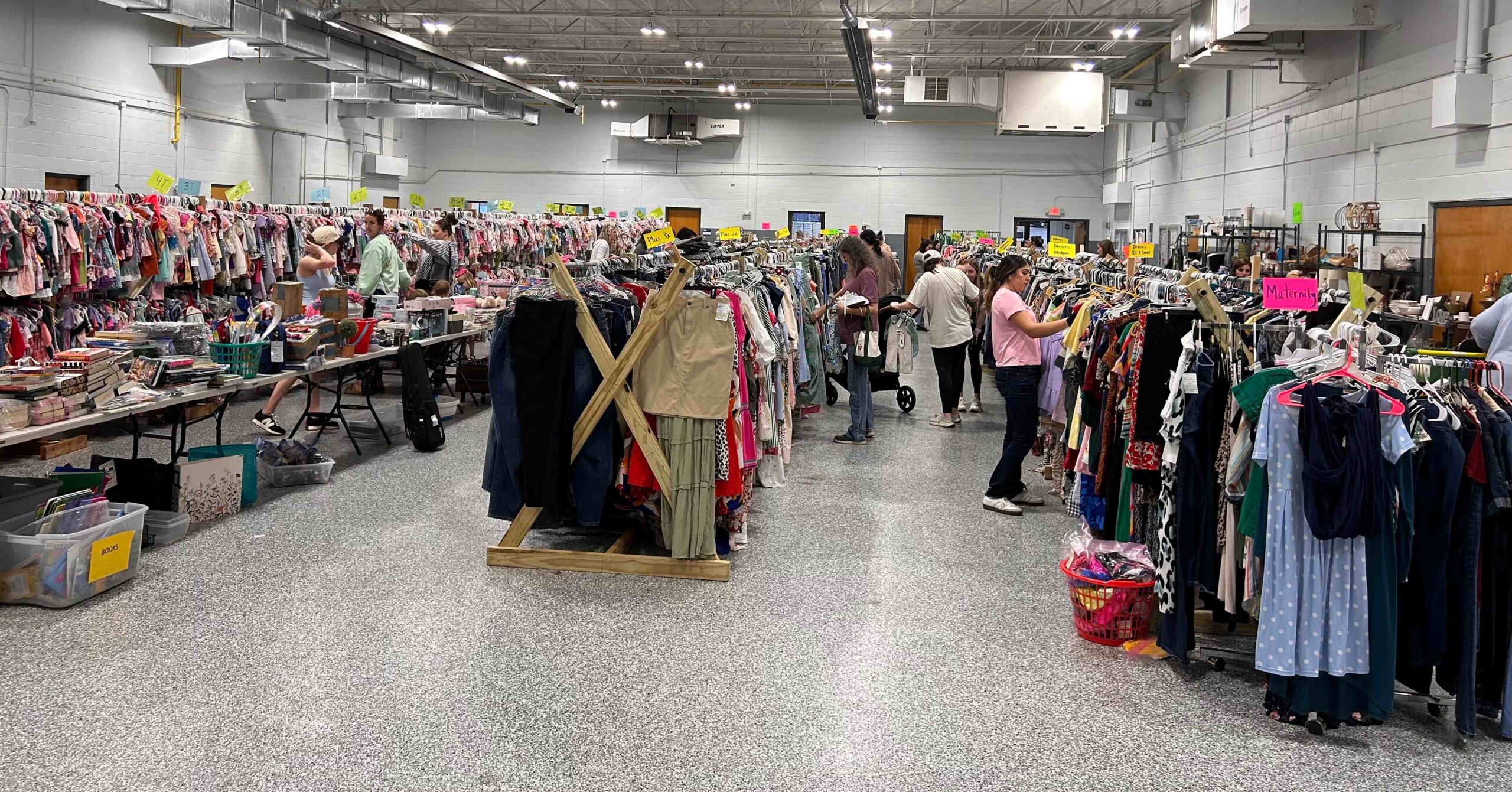 People searching through racks and racks of clothing, used books, shoes, and more at the Emerald City Consignment Sale
