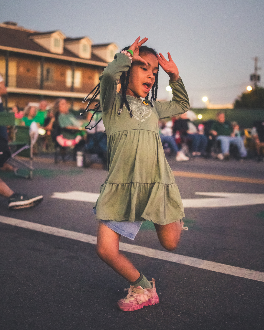 Little girl wearing a green dress dancing in the street during live music at St. Patrick's Music & Munchies.